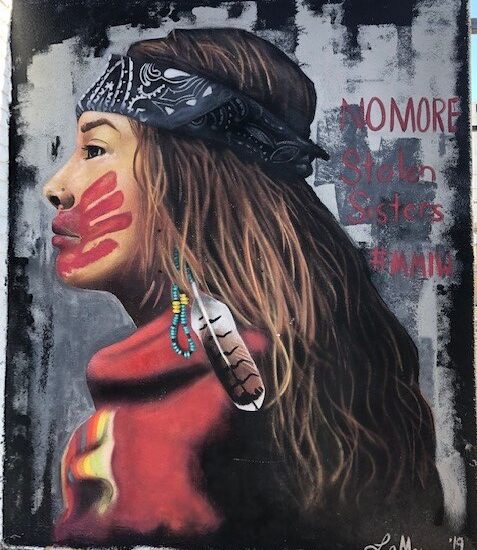 picture of a mural of a young Native American woman with a head band, wearing red and with a red hand print across her mouth